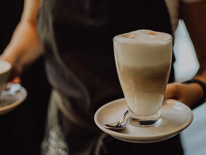 Eine Servicekraft mit zwei Tassen Kaffee in den Händen im Gourmet & Wellnesshotel Lürzerhof