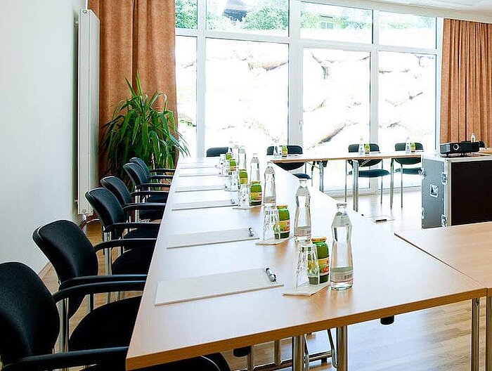 Heller Seminarraum mit voller Bestuhlung und Getränken an jedem Platz