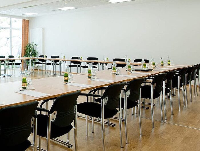 Heller Seminarraum mit voller Bestuhlung und Getränken an jedem Platz
