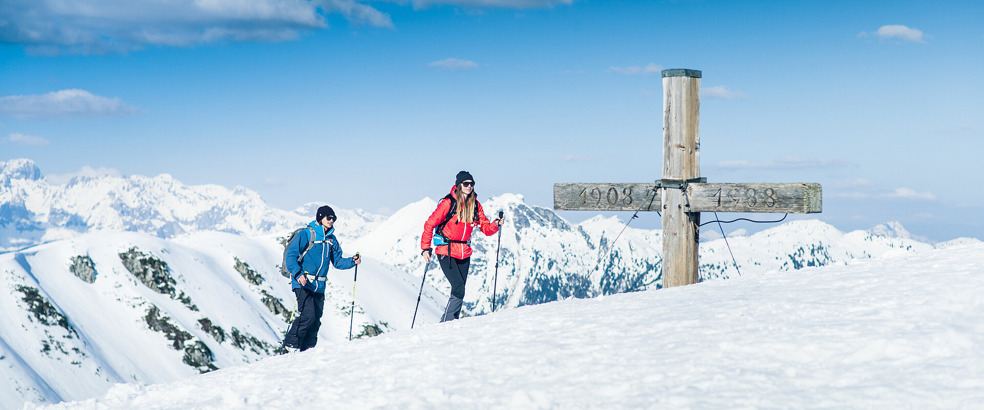 TVB_Shoot2 Zwei Skitourengeher am Gipfelkreuz mit Panoramablick auf verschneite Alpen in Obertauern