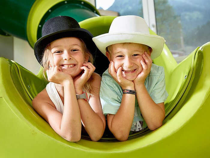 Zwei Kinder spielen auf einer Rutsche im Spielbereich des Lürzerhofs, dem Familienhotel in Österreich für Urlaub mit Kindern.