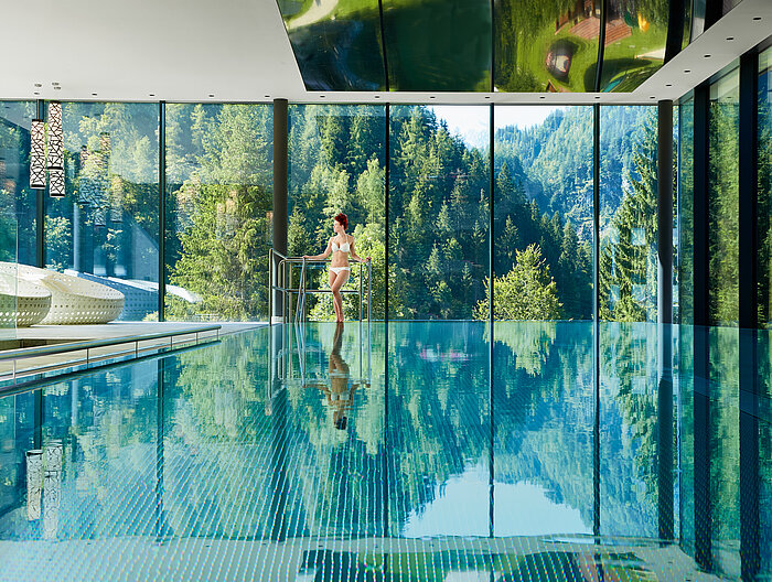 Eine Frau steht neben dem Indoorpool im Wellneshotel Lürzerhof in Salzburg