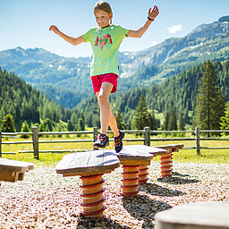 AllesAlm EIn Mädchen spielt auf einem Spielplatz des Alles Alm Erlebnisweges
