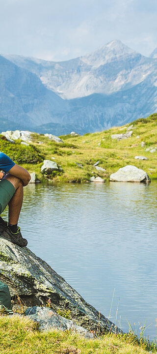 Sommershoot Zwei Wanderer sitzen auf Felsen am Bergsee in Obertauern
