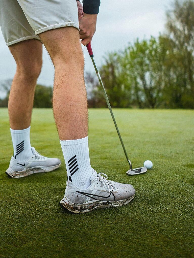 Golfen Golfer beim Putten mit Ball vor dem Loch auf dem Grün
