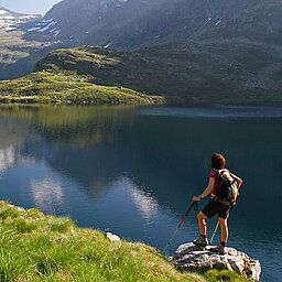 Eine Wanderin entspannt mit Blick auf den Bergsee während ihres Aktivurlaubs in Österreich