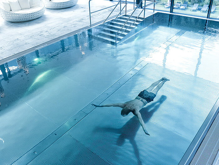 Ein Mann schwimmt im Indoorpool des Wellnesshotels Lürzerhof in Salzburg