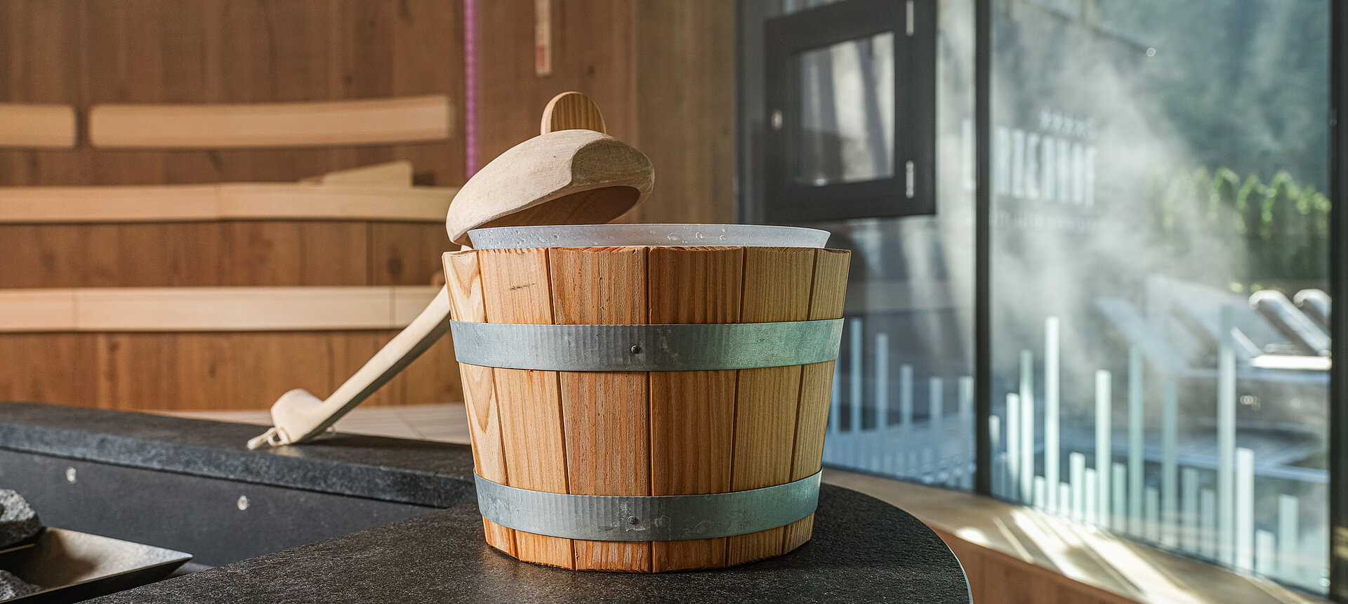 Saunabereich im Wellnesshotel Lürzerhof in Salzburg mit einem traditionellen Aufgusskübel aus Holz.