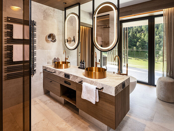 Luxusbad mit goldenen Waschbecken und Bergblick im Wellnesshotel nahe Obertauern