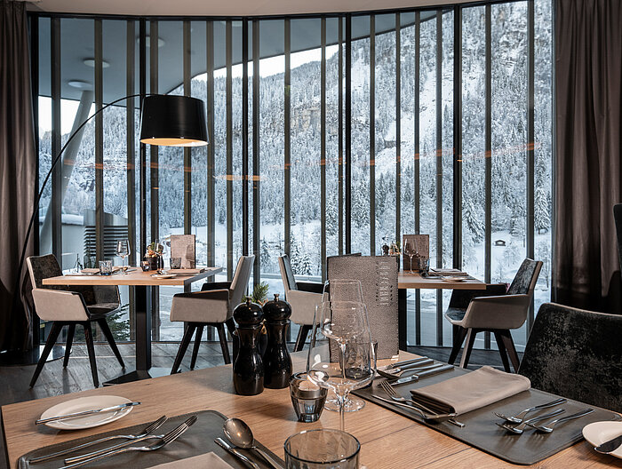 Ein stilvoll gedeckter Restaurantbereich im Lürzerhof Gourmet & Wellnesshotel mit Panoramablick auf die verschneite Berglandschaft.