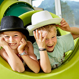 Zwei Kinder spielen auf einer Rutsche im Spielbereich im Hotel Lürzerhof