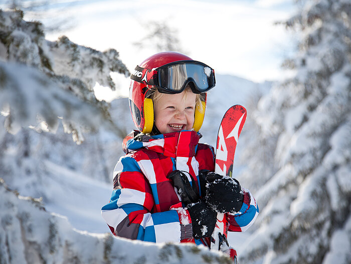 Kind mit Ski in der Hand im Skiurlaub in Obertauern