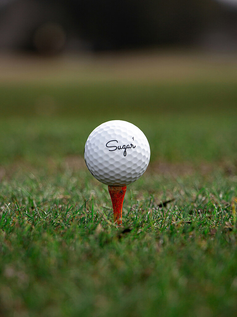 Golf Golfball auf rotem Tee auf einer Golfwiese
