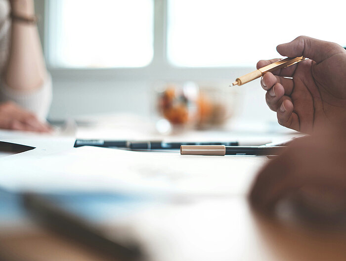 Besprechung am Tisch mit Stift und Dokumenten im Fokus