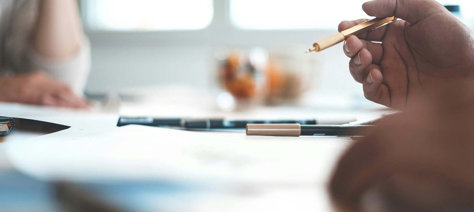 Besprechung am Tisch mit Stift und Dokumenten im Fokus