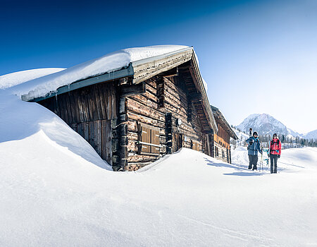 TVB_Shoot2 Zwei Skitourengeher vor verschneiter Berghütte bei strahlendem Winterwetter in Obertauern