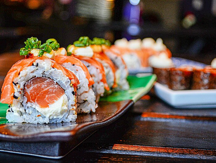 Sushi-Rollen mit Lachs und Frischkäse auf Keramikteller serviert
